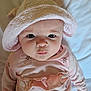baby, infant, child, pink_clothing, hat, cute, face, portrait, eyes, skin, lying_down, bed, soft_lighting, indoors, expression, headwear, young_child, person, sleepwear, newborn