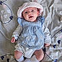 baby, infant, smiling, hat, blue_dress, white_socks, blanket, heart_pattern, cute, lying_down, child, face, happy, soft_lighting, indoors, portrait, young, small_hands, clothing, pink
