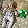 Eliora joined the competition — help win amazing prizes! baby, infant, smile, hat, pajamas, bed, pillow, stuffed_animal, green_toy, blanket, child, cute, lying_down, soft_toy, indoor, person, cozy, sleepwear, expression, happy