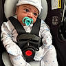 Alexander is registered to the contest to win money with this photo: baby, infant, car_seat, pacifier, onesie, hat, safety_straps, black_straps, white_clothing, blue_patterns, close_up, seated, child, cute, indoors, safety_label, car_safety, newborn, face, headwear