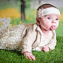 baby, infant, child, cute, tongue_out, lace_dress, knitted_cardigan, headband, flower_headband, grass, greenery, outdoor, portrait, playful, expression, skin, face, eyes, hand, background