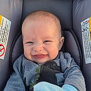 Jensen is registered to the contest to win money with this photo: baby, blanket, blue_mitten, car_seat, child, clothing, cute, expression, face, grey_clothing, hands, indoors, infant, person, portrait, scrunched_face, seated, smile, warning_labels, young_child