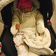 Kira a rejoint le concours — aidez-le/la à gagner de superbes lots ! baby, infant, sleeping, stroller, blanket, pink_hat, winter_clothing, padded_suit, toy, beads, indoor, child, cute, cozy, warm, face, hand, footwear, person, toddler