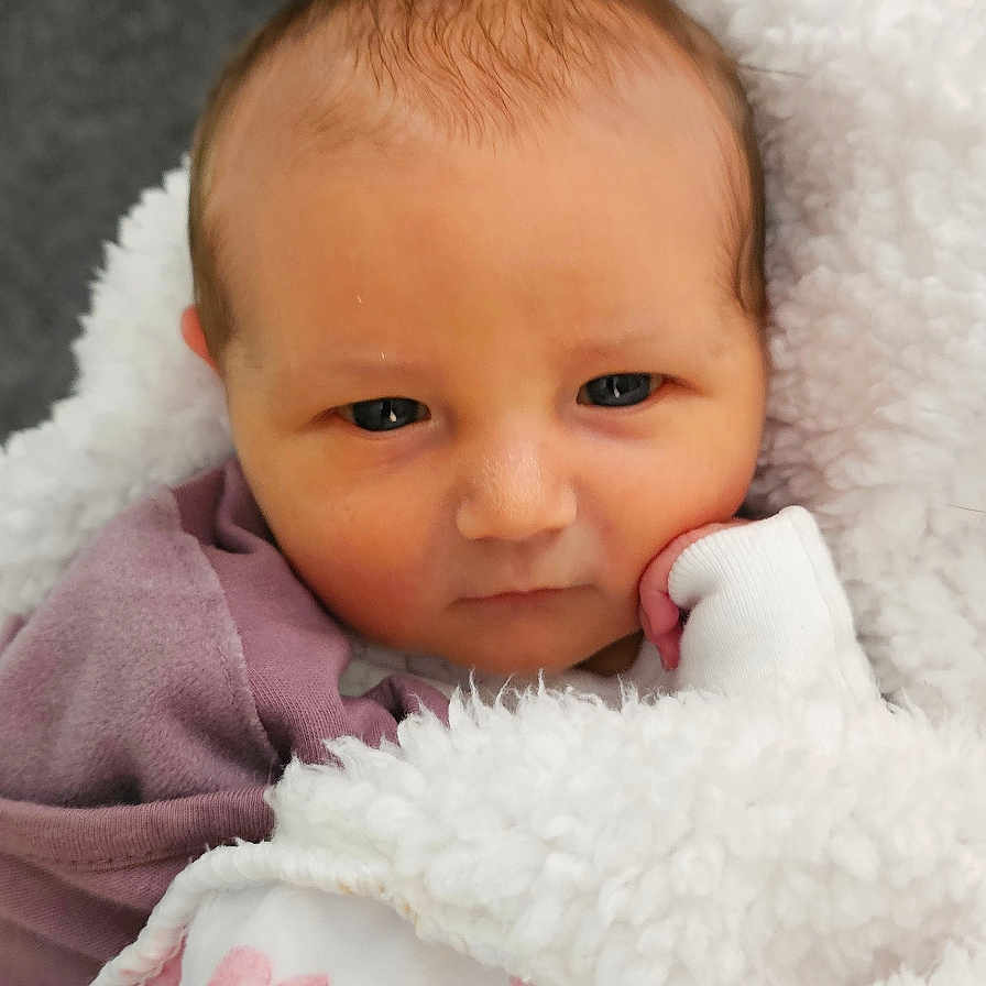 Layla joined the competition — help win amazing prizes! baby, blanket, clothing, cozy, cute, face, hand, head, indoors, infant, newborn, person, pink, portrait, resting, skin, sleepwear, soft_texture, warm, white