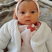 Lyana a rejoint le concours — aidez-le/la à gagner de superbes lots ! baby, infant, headband, bow, knitted_cardigan, blanket, floral_pattern, hand, face, eyes, clothing, portrait, cute, newborn, indoor, soft_texture, warm, young_child, person, closeup