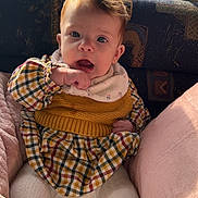 Capucine participe au concours pour gagner de l'argent avec cette photo : baby, child, cozy, cushion, dress, expression, eyes, face, hair, hand, indoors, infant, knitwear, natural_light, pink, plaid, portrait, sitting, window, yellow