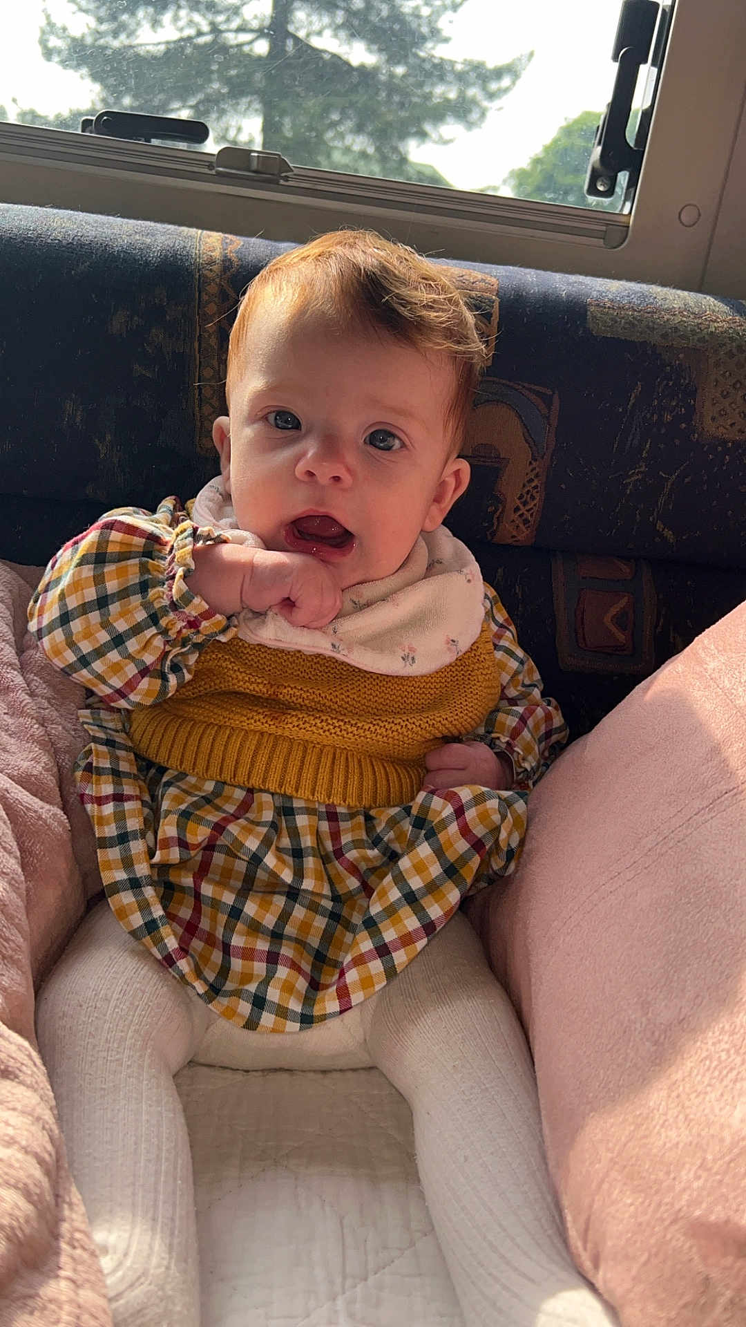 Capucine participe au concours pour gagner de l'argent avec cette photo : baby, child, cozy, cushion, dress, expression, eyes, face, hair, hand, indoors, infant, knitwear, natural_light, pink, plaid, portrait, sitting, window, yellow