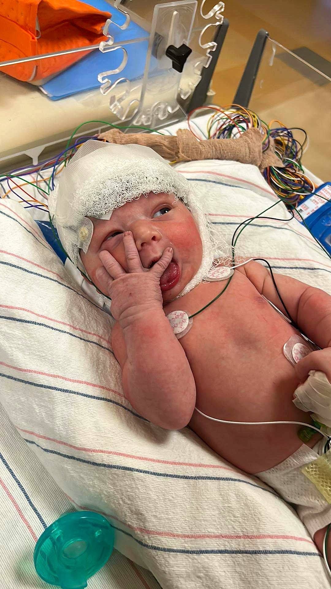 Hudson is registered to the contest to win money with this photo: abdomen, baby, barechested, bedding, chest, child, comfort, event, finger, flesh, headwear, hospital, human_body, linens, medical_equipment, mouth, patient, person, room, service