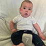 Cassidy is registered to the contest to win money with this photo: baby, child, infant, face, kiss_mark, white_shirt, dark_pants, plush_block, number_seven, barefoot, sitting, soft_blanket, indoors, portrait, cute, expression, young_child, candid, skin, head