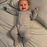 arms_raised, baby, bed, bedroom, blanket, child, clothing, cuddly, happy, home, indoor, infant, lying_down, pacifier, photography, pillow, portrait, smiling, striped_onesie, stuffed_animal