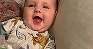 Greyson is registered to the contest to win money with this photo: baby, child, infant, smiling, happy, portrait, face, sitting, lying_down, bed, pillow, blanket, bottle, feeding, onesie, clothing, indoor, bedroom, cozy, baby_toy