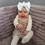 Lou a rejoint le concours — aidez-le/la à gagner de superbes lots ! baby, bow, child, couch, cozy, cute, dress, floral, furniture, happy, headband, indoors, infant, person, playful, plush, portrait, sitting, smiling, tights