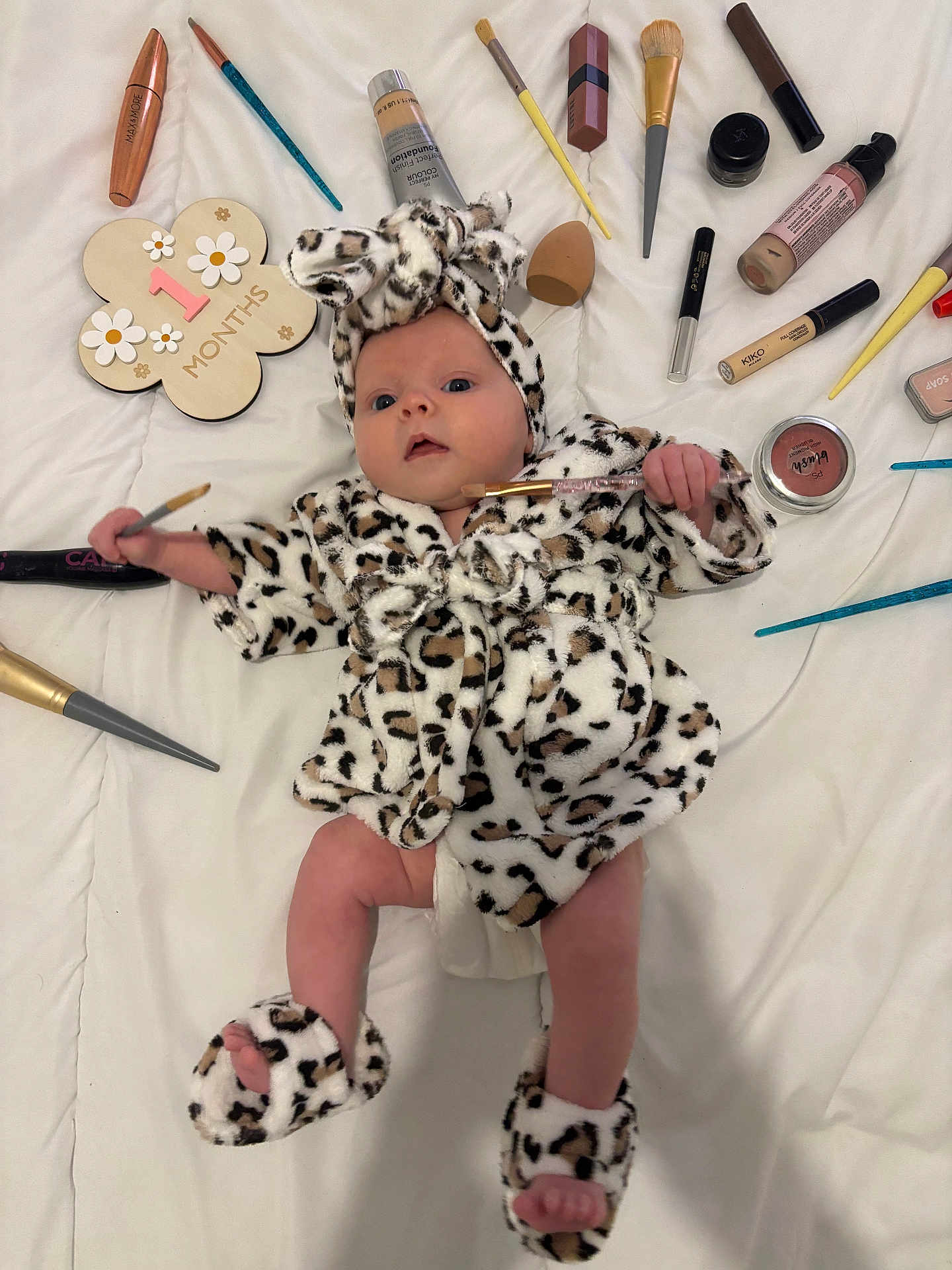 Lou a rejoint le concours — aidez-le/la à gagner de superbes lots ! baby, infant, leopard_print, robe, slippers, makeup_brush, foundation, cosmetics, white_sheet, sign, 1_month, face, hand, foot, lying_down, cute, newborn, headband, soft_texture, skin