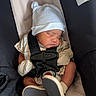 baby, infant, sleeping, car_seat, hat, mittens, straps, clothing, footwear, seat_belt, child, cute, newborn, resting, indoors, portrait, soft_lighting, comfort, safety, peaceful