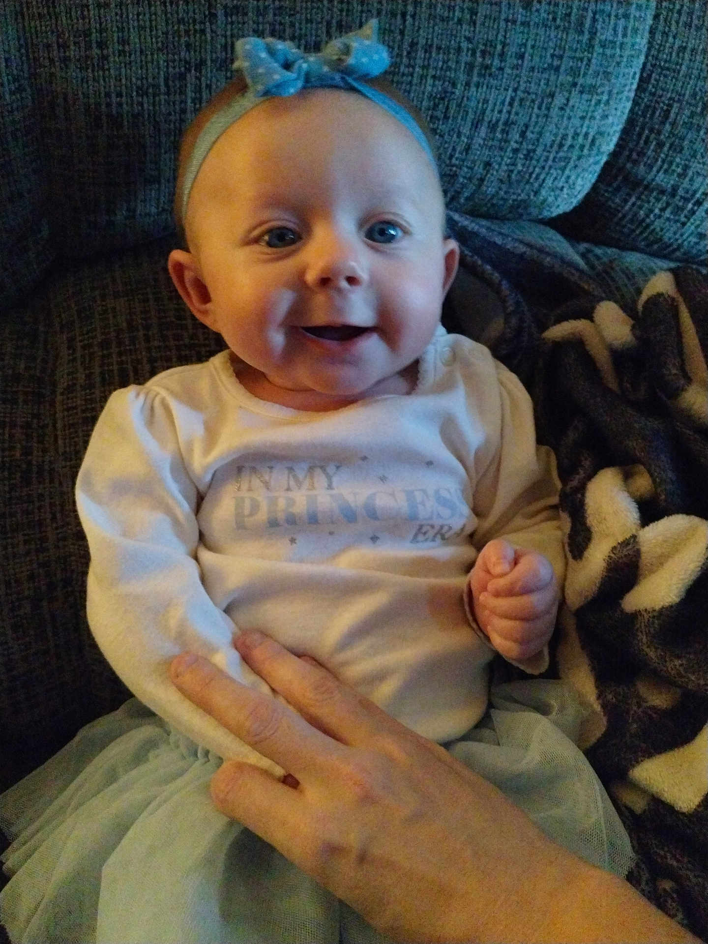 Bailey Lee joined the competition — help win amazing prizes! baby, blanket, bow, child, clothing, couch, cozy, cute, face, hand, happy, headband, indoor, infant, person, portrait, sitting, smiling, soft, tutu