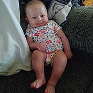 Bailey Lee is registered to the contest to win money with this photo: baby, blanket, child, couch, cozy, feet, floral_pattern, furniture, happy, head, home, indoor, infant, legs, onesie, person, relaxed, sitting, skin, smile