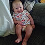 baby, blanket, child, couch, cozy, feet, floral_pattern, furniture, happy, head, home, indoor, infant, legs, onesie, person, relaxed, sitting, skin, smile