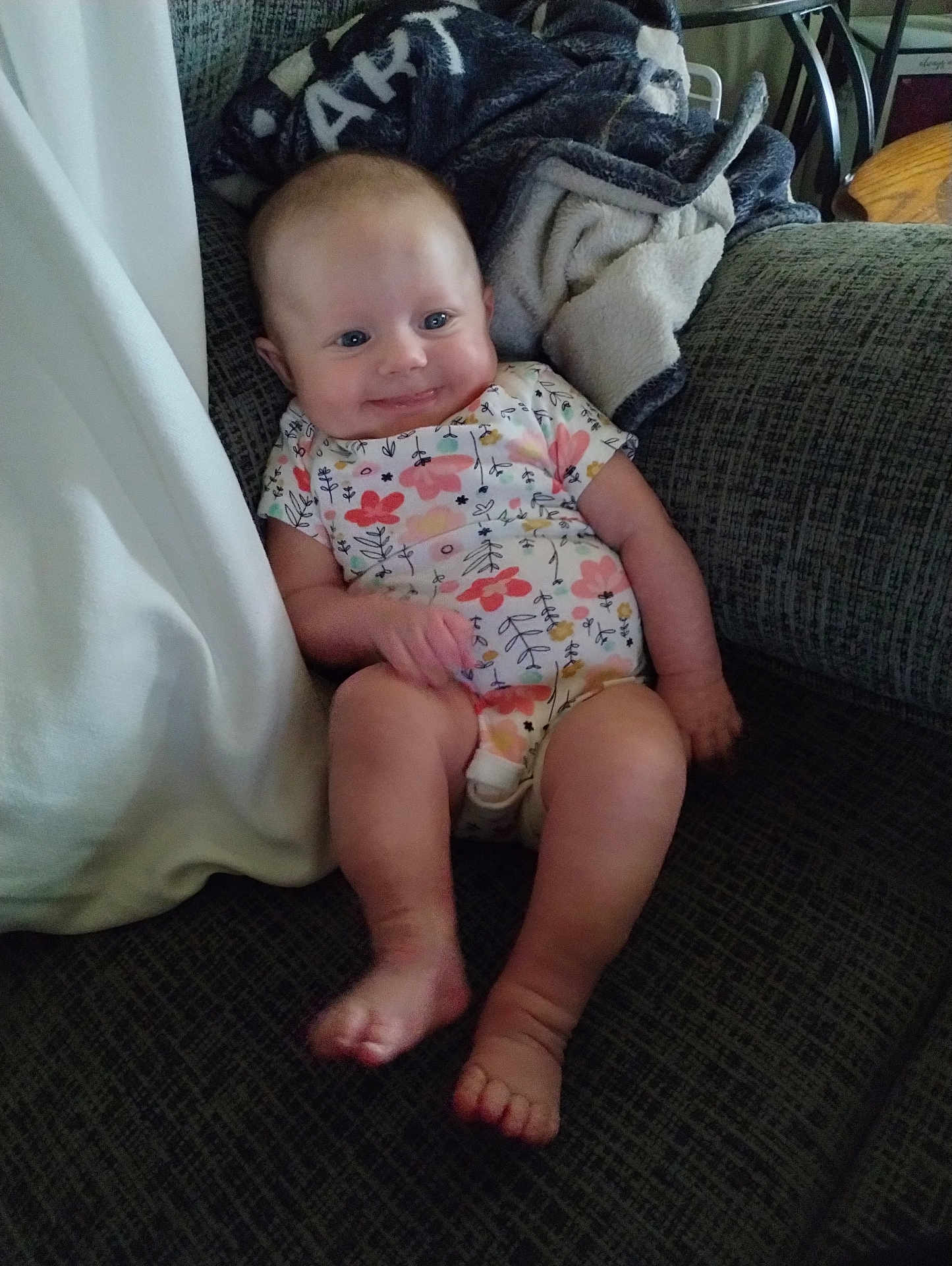 Bailey Lee is registered to the contest to win money with this photo: baby, blanket, child, couch, cozy, feet, floral_pattern, furniture, happy, head, home, indoor, infant, legs, onesie, person, relaxed, sitting, skin, smile