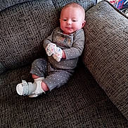 Bailey Lee joined the competition — help win amazing prizes! baby, child, comfortable, couch, cozy, cute, footwear, furniture, gray, home, indoor, infant, mittens, pajamas, person, polka_dot, sitting, smiling, soft_lighting, white