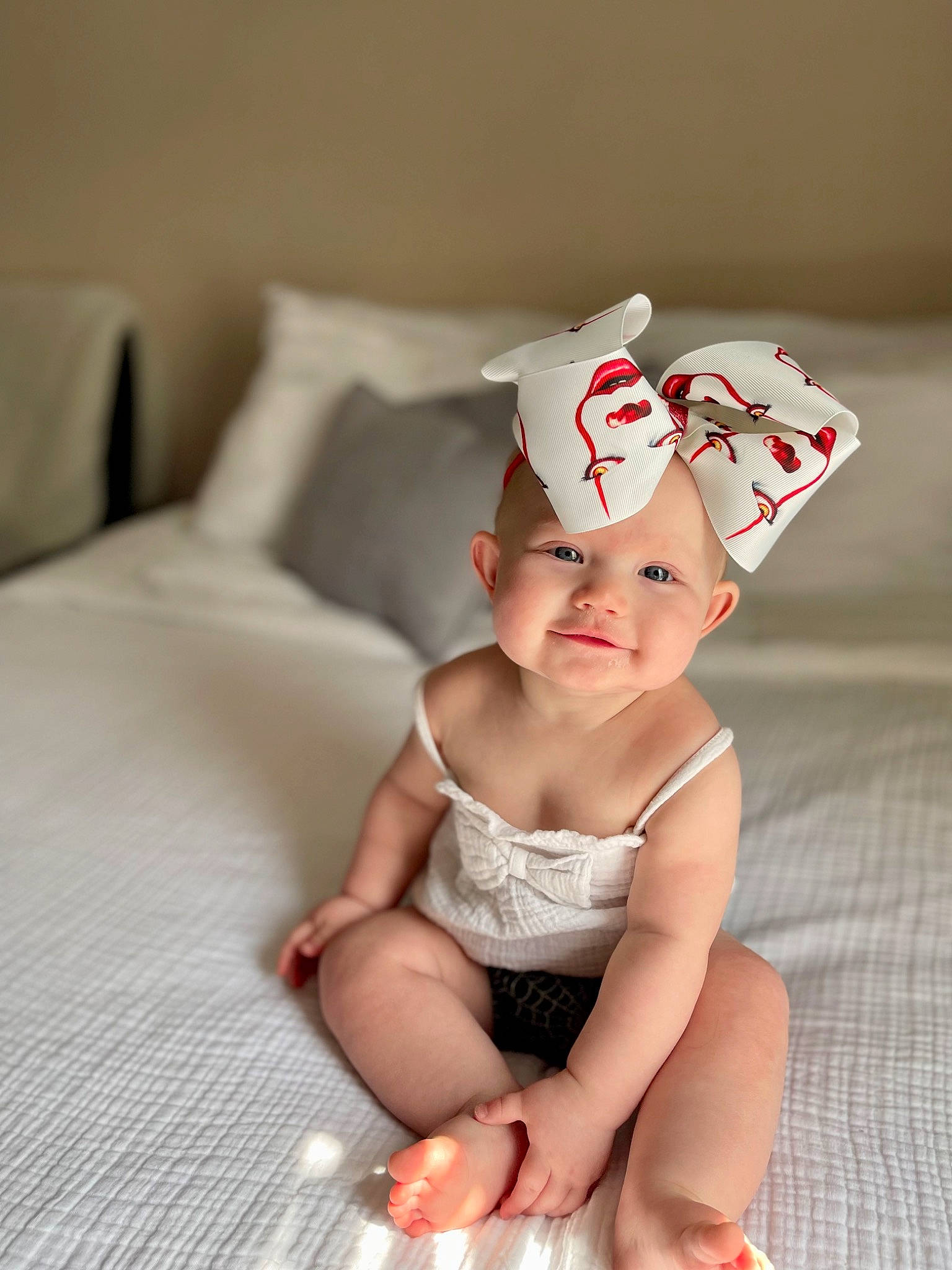 Laila is registered to the contest to win money with this photo: baby, baby_toddler_clothing, cap, child, comfort, eye, face, fashion_accessory, flooring, foot, fun, happy, head, headwear, human_body, human_leg, knee, linens, person, sitting