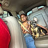 girl, child, dog, french_bulldog, pet, car, vehicle, backseat, seatbelt, leather_seats, sitting, companion, indoor, travel, family, portrait, ears, puppy, pink_backpack, daylight