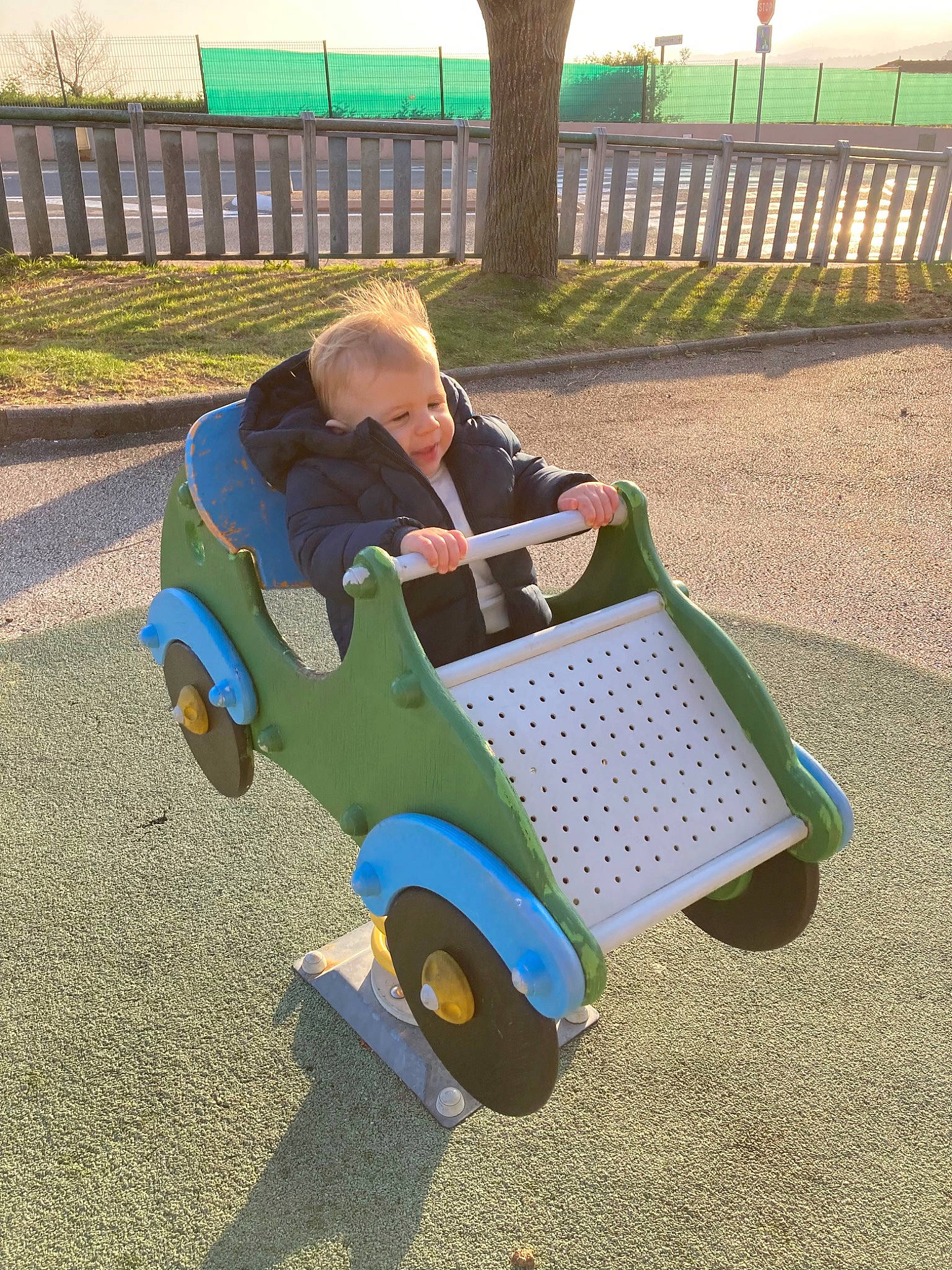 Rio participe au concours pour gagner de l'argent avec cette photo : bench, city, comfort, electric_blue, fence, fun, grass, leisure, outdoor_furniture, people_in_nature, person, plant, recreation, rolling, shade, sitting, tire, toddler, tree, vehicle
