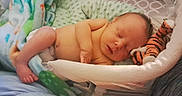 Griffin is registered to the contest to win money with this photo: baby, newborn, sleeping, plush_toy, tiger, blanket, cushion, diaper, infant, cozy, resting, cute, peaceful, child, soft_texture, bed, portrait, indoors, toddler, person