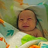 baby, blanket, child, colorful, cozy, cute, expression, face, happy, indoors, infant, lying_down, newborn, peaceful, portrait, skin, smile, soft, warm, wrapped