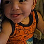 baby, child, infant, tongue_out, orange_outfit, cute, smiling, face, skin, arm, legs, patterned_clothing, closeup, indoors, person, playful, expression, cozy, soft, young