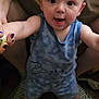 baby, child, person, blue_clothing, standing, indoor, adult_hand, floor, shirt, logo, burger_king, support, smiling, happy, footwear, nail_polish, holding, human, cute, expression