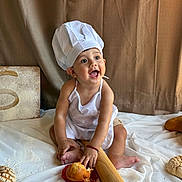 Luis Adriel is registered to the contest to win money with this photo: baby, child, chef_hat, apron, bread, pastries, rolling_pin, smile, happy, sitting, food, baking, kitchen, white_cloth, cute, infant, portrait, indoors, playful, cooking