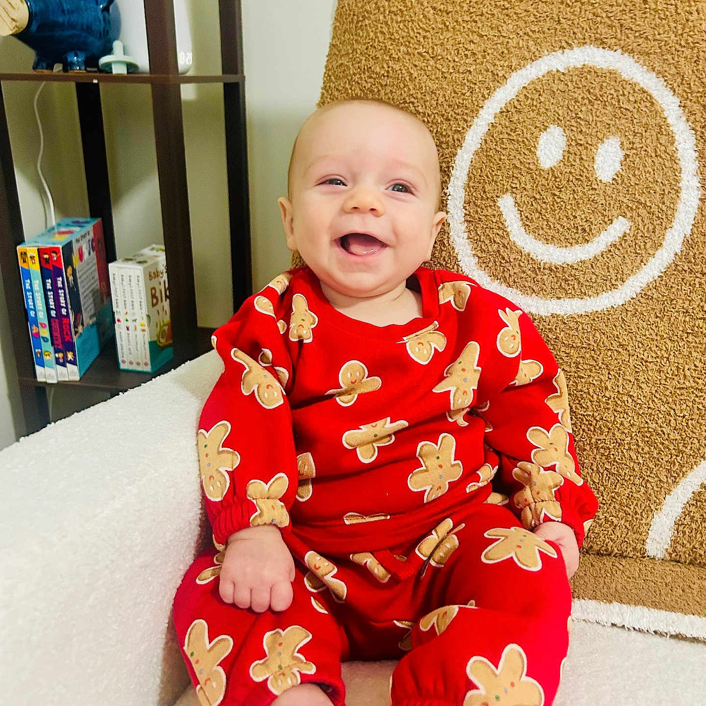 Caden is registered to the contest to win money with this photo: baby, blanket, books, bookshelf, chair, child, cozy, cute, face, foot, furniture, gingerbread_pattern, hand, happy, indoors, portrait, red_clothing, sitting, smiley_face, smiling