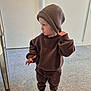 Carson is registered to the contest to win money with this photo: toddler, child, brown_clothing, beanie, sweatshirt, sweatpants, white_sneakers, indoor, carpet, floor, standing, casual, portrait, fashion, cute, childrens_fashion, hat, looking_away, person, young_child