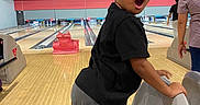 Promise joined the competition — help win amazing prizes! child, bowling, bowling_alley, bowling_lane, surprised, wide_eyes, open_mouth, portrait, indoor, recreation, sports, black_shirt, gray_pants, bowling_pins, bowling_ball, seating, wooden_floor, family_activity, background_people, photography