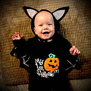 Ava joined the competition — help win amazing prizes! baby, child, costume, halloween, pumpkin, bat_wings, smiling, cute, black_clothing, headwear, holiday, celebration, infant, lying_down, blanket, happy, face, festive, indoors, portrait