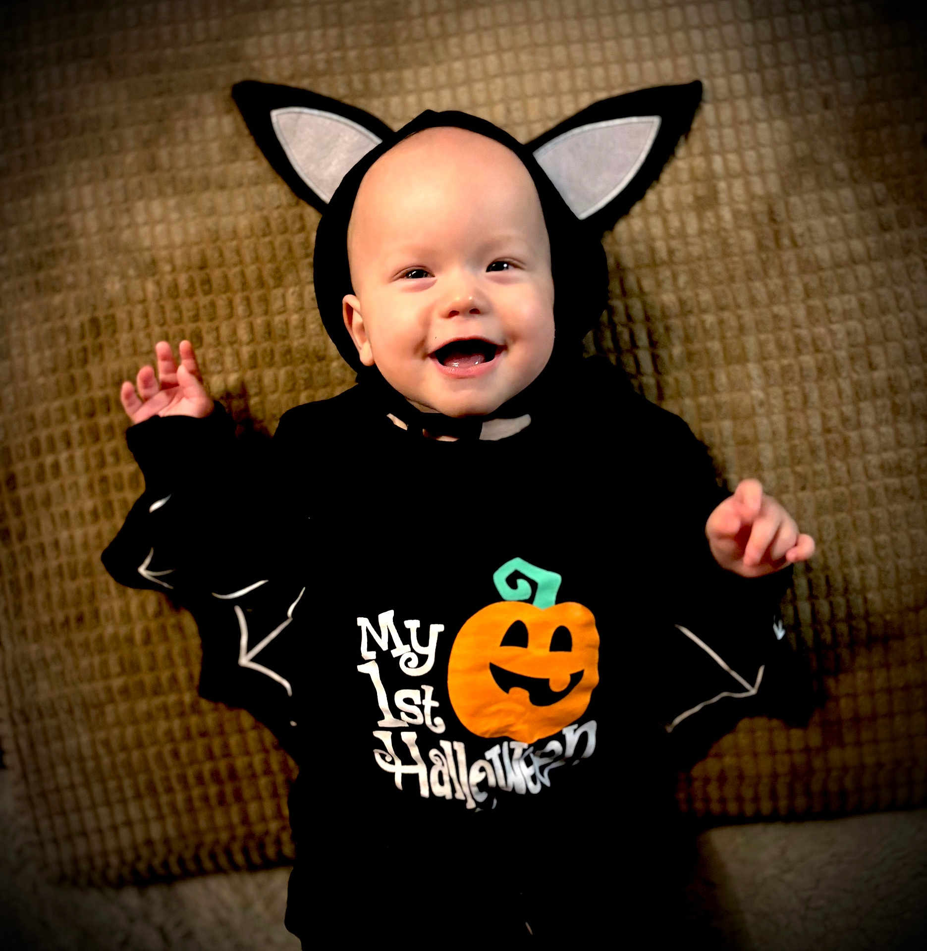 Ava joined the competition — help win amazing prizes! baby, child, costume, halloween, pumpkin, bat_wings, smiling, cute, black_clothing, headwear, holiday, celebration, infant, lying_down, blanket, happy, face, festive, indoors, portrait
