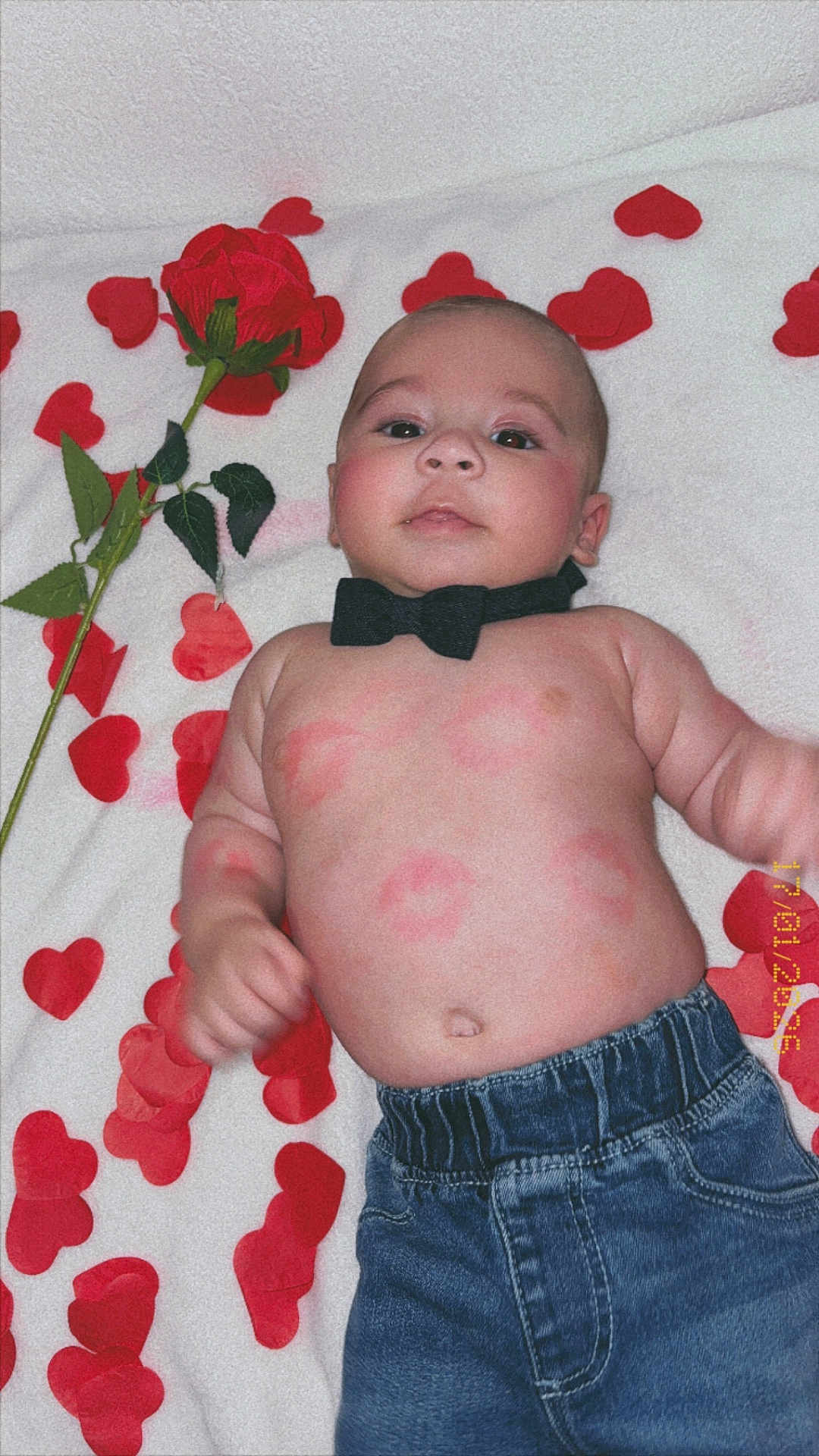 Ewen a rejoint le concours — aidez-le/la à gagner de superbes lots ! baby, infant, bow_tie, denim_pants, red_rose, heart_petals, blanket, face, skin, cute, lying_down, kiss_marks, love, adorable, child, portrait, casual_clothing, indoor, happy, closeup