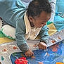 baby, infant, onesie, water_play_mat, toy, floor, carpet, colorful, sea_creatures, octopus, starfish, turtle, fish, curious, child, indoor, play, hands, exploration, soft_lighting