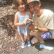 Natalie joined the competition — help win amazing prizes! animal, cap, casual_clothing, child, daytime, forest, happy, holding, leaves, man, nature, outdoor, people, reptile, smile, sneakers, sunlight, together, trail, turtle