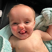 Harmony joined the competition — help win amazing prizes! baby, tongue, towel, skin, face, expression, child, playful, adorable, hair, lying_down, happy, infant, cute, closeup, smile, bare_chest, blue_towel, person, indoors