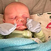 Adtikus is registered to the contest to win money with this photo: baby, sleeping, blanket, mittens, infant, cozy, face, bed, cushion, pattern, footprints, clothing, soft, peaceful, resting, child, closeup, indoors, cute, young