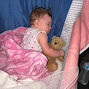 Amelia is registered to the contest to win money with this photo: baby, sleeping, blanket, teddy_bear, crib, pink, blue, child, soft_toy, cushion, infant, resting, cute, cozy, indoors, person, bedtime, peaceful, sleepwear, adorable