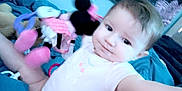 Amelia is registered to the contest to win money with this photo: baby, child, infant, onesie, toy, plush, minnie_mouse, bed, blanket, blue, tapestry, pattern, indoor, person, face, smile, legs, arm, room, cute