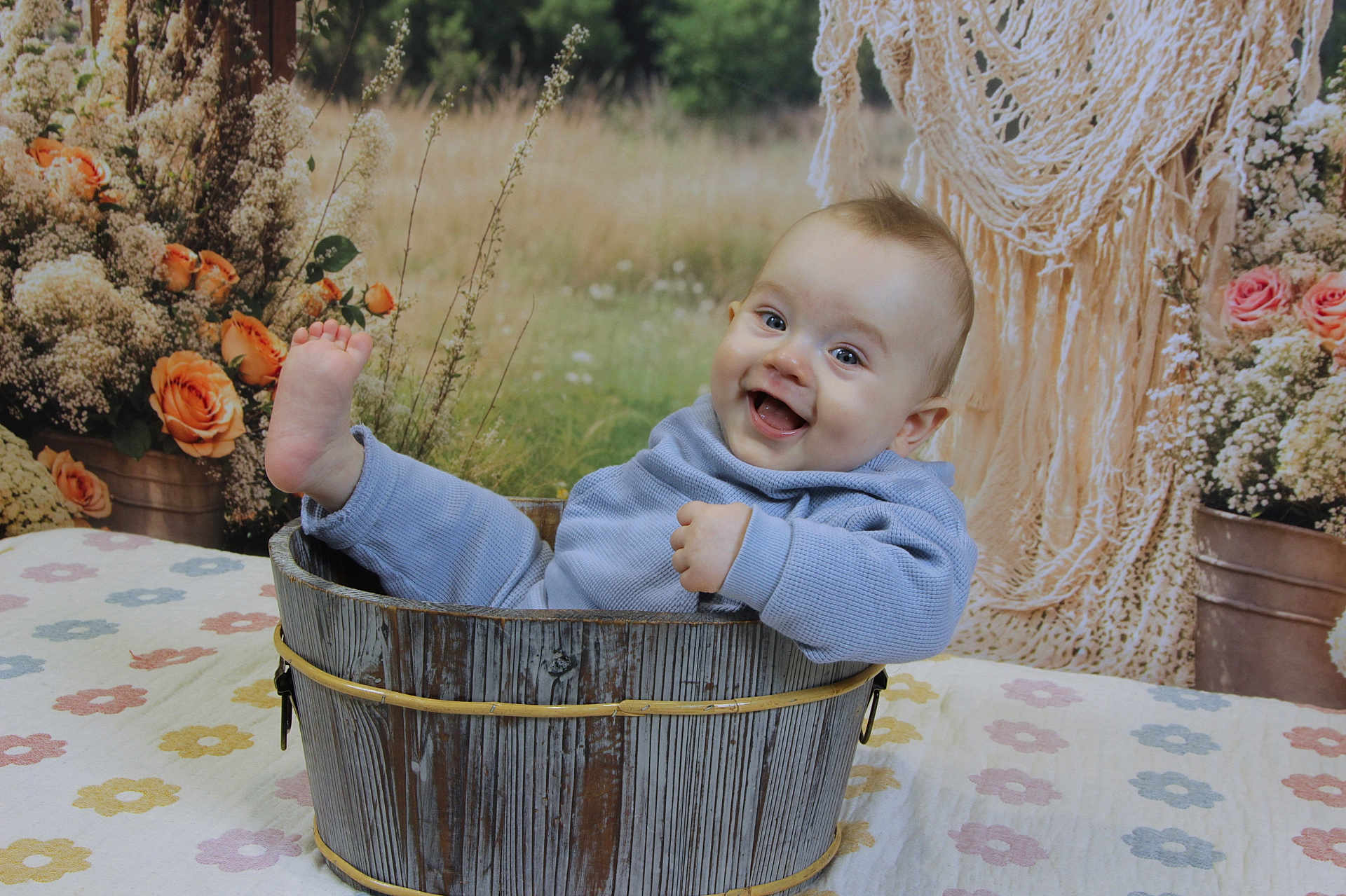 Noé a rejoint le concours — aidez-le/la à gagner de superbes lots ! baby, bucket, blue_clothing, smiling, happy, flower_arrangement, wooden_bucket, macrame, indoor, portrait, child, cute, foot_up, tablecloth, floral_pattern, decor, cozy, infant, sitting, background