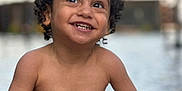 Gonçalves a rejoint le concours — aidez-le/la à gagner de superbes lots ! child, toddler, smiling, curly_hair, water, outdoor, playing, happy, bare_chest, skin, face, person, summer, daylight, nature, fun, joy, cute, young, portrait