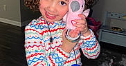 Aria is registered to the contest to win money with this photo: celebration, child, childhood, colorful_clothing, curly_hair, cute, face, floor, happy, holiday, home, indoor, pajamas, person, pink_bird, play, smiling, stuffed_toy, toys, wrapping_paper