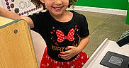 Aria joined the competition — help win amazing prizes! birthday_outfit, black_shirt, child, colorful_background, curly_hair, cute, educational_posters, girl, happy, indoor, learning_environment, person, play_area, play_checkout, polka_dots, preschool, red_skirt, retail_setup, smiling, toy_register