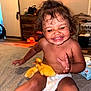 toddler, child, diaper, duckling, animal, pet, indoor, carpet, smile, happy, cute, baby, playing, young_child, yellow_duck, furniture, home, face, sitting, expression