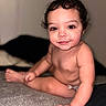 Xavier is registered to the contest to win money with this photo: baby, child, infant, curly_hair, smiling, portrait, sitting, indoor, blanket, bed, home, face, eyes, hands, legs, barefoot, diaper, candid, happy, photography