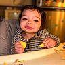 Xavier is registered to the contest to win money with this photo: baby, child, toddler, high_chair, eating, food, fruit, hands, smiling, face, portrait, indoor, home, kitchen, table, messy, striped_clothing, seated, happy, photograph